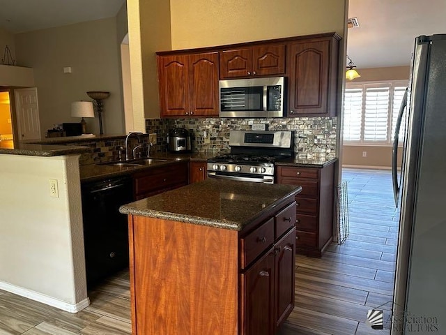 kitchen featuring dark stone counters, sink, decorative backsplash, appliances with stainless steel finishes, and kitchen peninsula