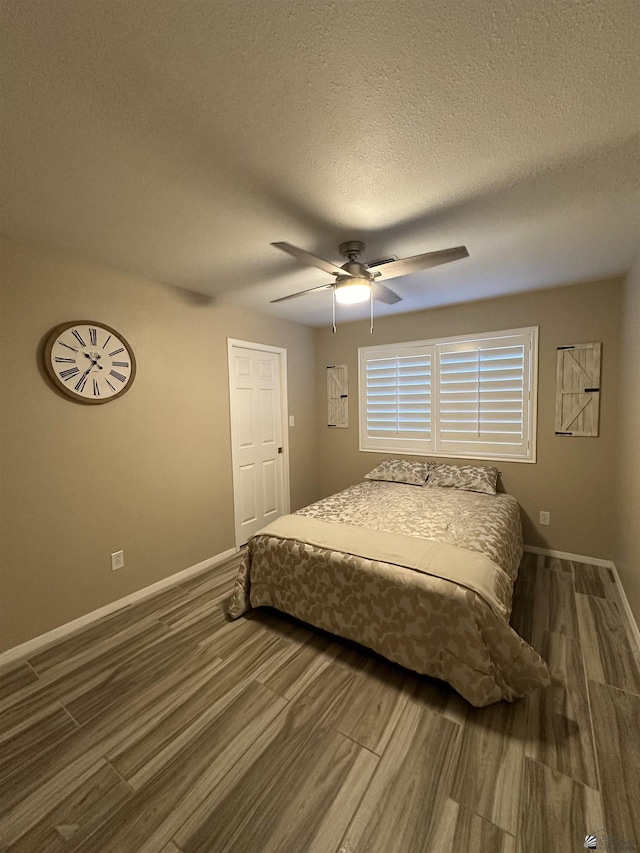 bedroom with a textured ceiling, ceiling fan, and dark wood-type flooring