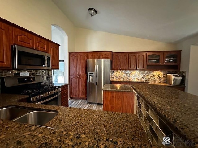 kitchen with sink, dark stone counters, lofted ceiling, decorative backsplash, and appliances with stainless steel finishes