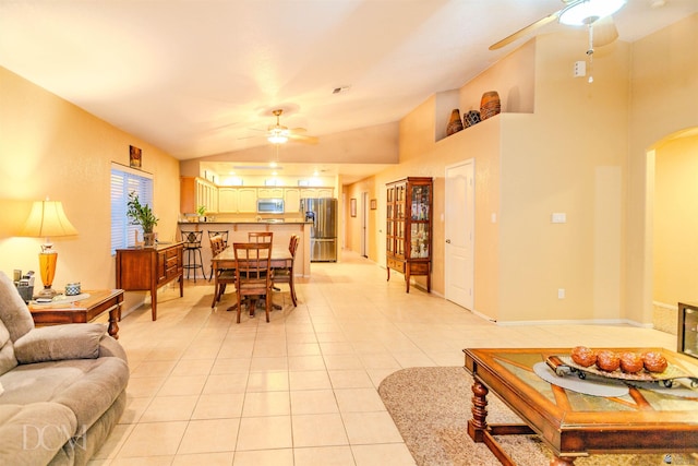 living room with ceiling fan, lofted ceiling, and light tile patterned flooring