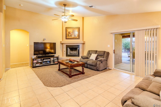 living room featuring a fireplace, ceiling fan, lofted ceiling, and light tile patterned flooring