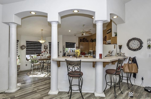 kitchen with ornate columns, a breakfast bar area, ceiling fan, and decorative light fixtures