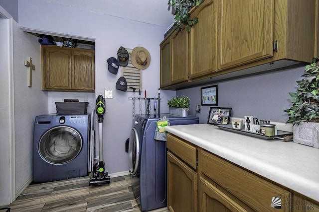 clothes washing area with separate washer and dryer, dark wood-type flooring, and cabinets