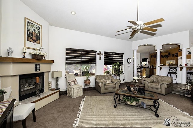 living room featuring decorative columns, ceiling fan, and dark colored carpet