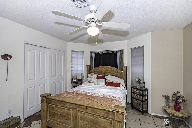 bedroom featuring ceiling fan, a textured ceiling, a closet, and light tile patterned floors