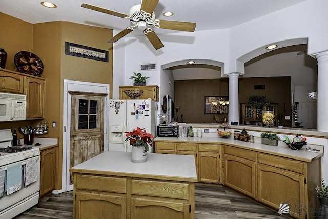 kitchen featuring white appliances, dark wood-type flooring, ceiling fan, a kitchen island, and kitchen peninsula