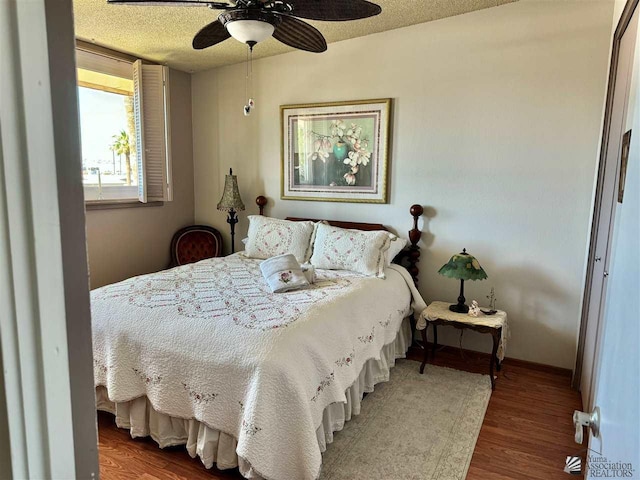 bedroom featuring ceiling fan, a textured ceiling, baseboards, and wood finished floors