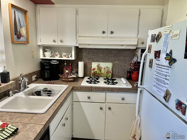 kitchen featuring under cabinet range hood, white appliances, a sink, white cabinets, and decorative backsplash