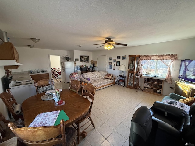 dining area with ceiling fan, sink, and a textured ceiling