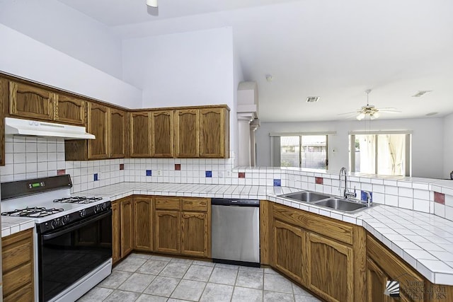 kitchen featuring sink, gas range, tasteful backsplash, tile countertops, and dishwasher