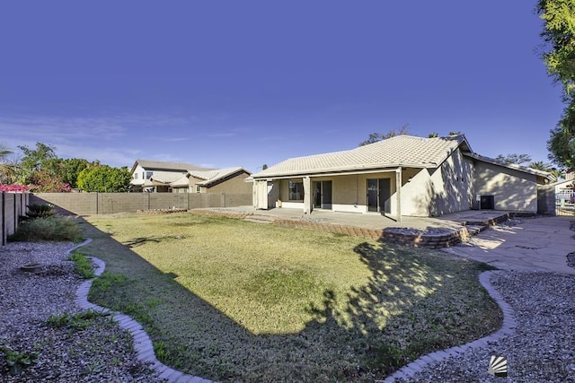 back of house with a lawn and a patio