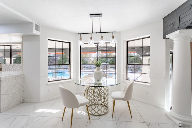 dining space with a textured ceiling, a wealth of natural light, and ornate columns