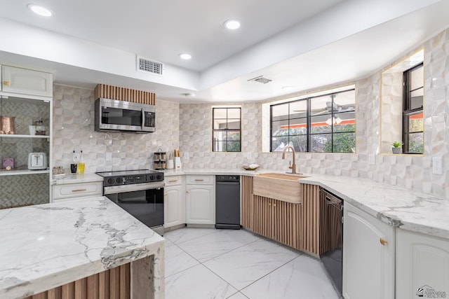 kitchen featuring white cabinets, decorative light fixtures, black dishwasher, sink, and backsplash