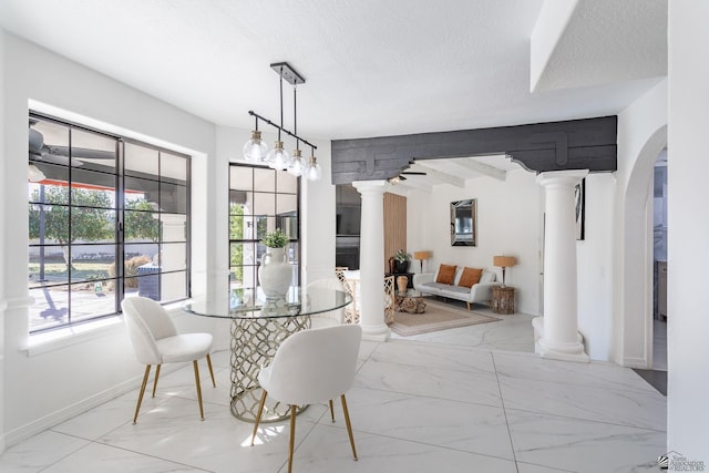 dining space with decorative columns, a textured ceiling, and beamed ceiling