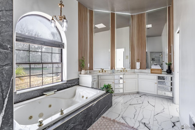 bathroom featuring tiled bath, a notable chandelier, and vanity