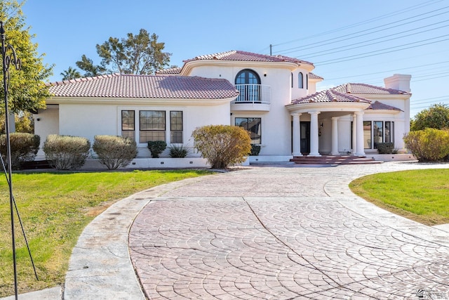 mediterranean / spanish home featuring a balcony and a front lawn