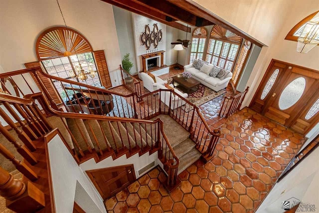 stairway featuring a high ceiling, an inviting chandelier, and beam ceiling