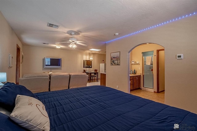 bedroom with ensuite bathroom, a textured ceiling, and light tile patterned floors