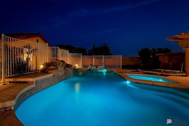 pool at night with an in ground hot tub