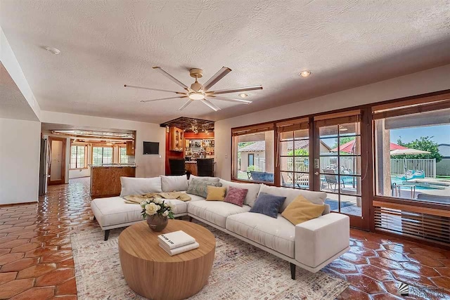 living room with ceiling fan, french doors, and a textured ceiling