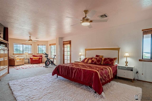 bedroom with ceiling fan, carpet flooring, and a textured ceiling