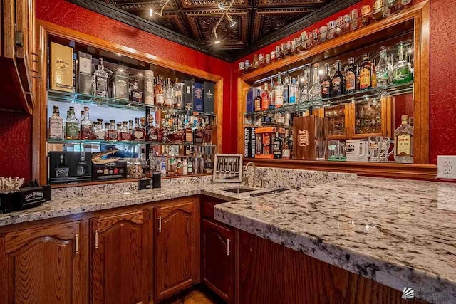 bar featuring sink and light stone counters