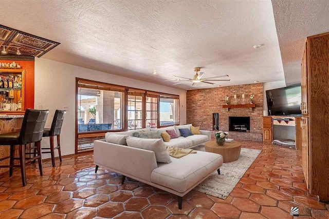 living room featuring ceiling fan, indoor bar, a fireplace, and a textured ceiling