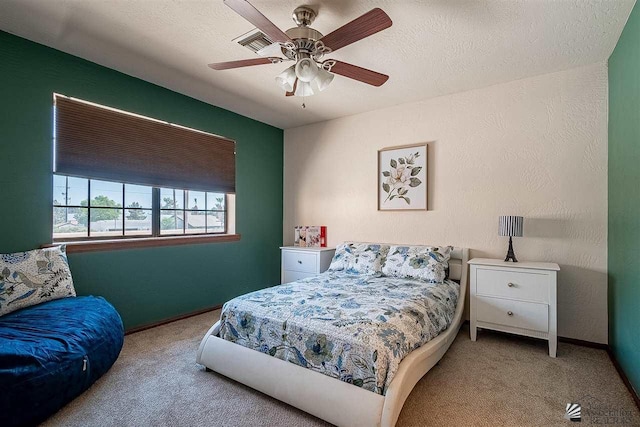 bedroom with ceiling fan, light colored carpet, and a textured ceiling