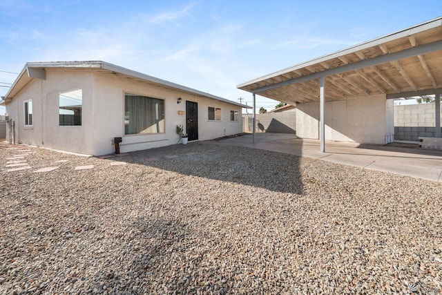 rear view of house with fence and stucco siding