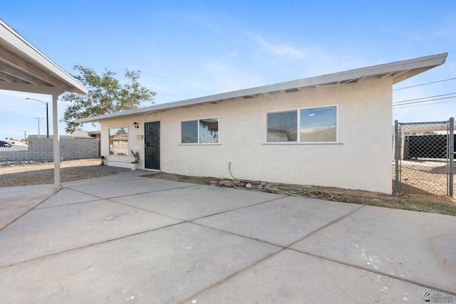 back of house with a patio area, fence, and stucco siding