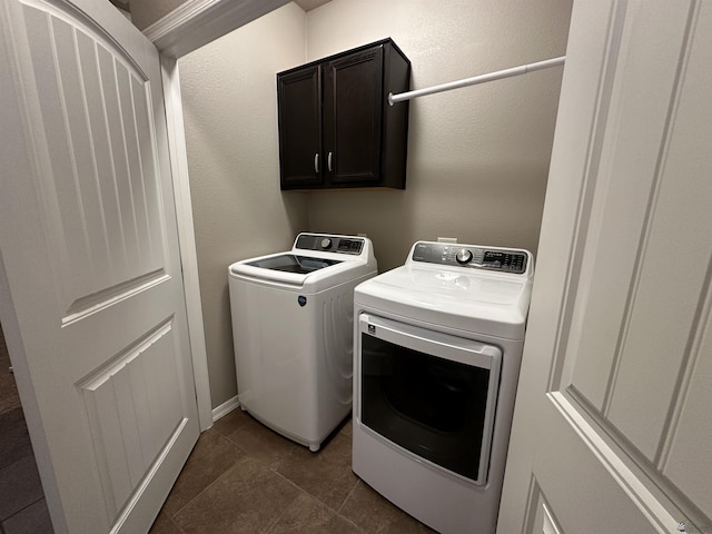 clothes washing area with washer and clothes dryer and cabinets