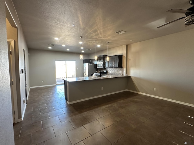 kitchen featuring sink, ceiling fan, stainless steel appliances, decorative backsplash, and kitchen peninsula