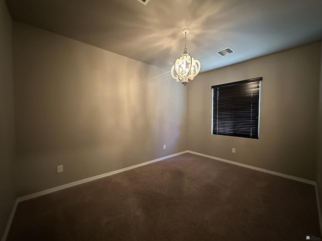 carpeted empty room featuring a chandelier