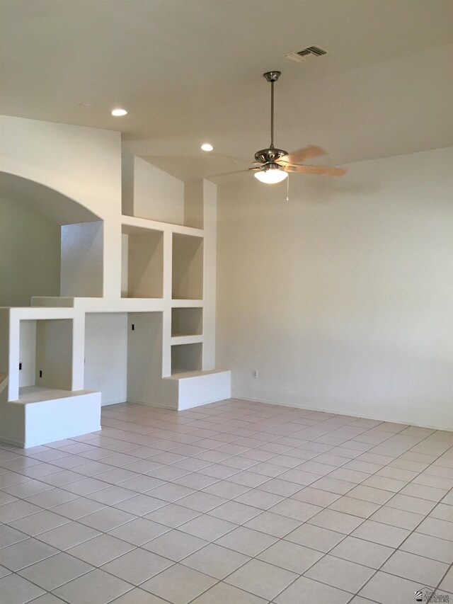 tiled empty room featuring ceiling fan and built in features