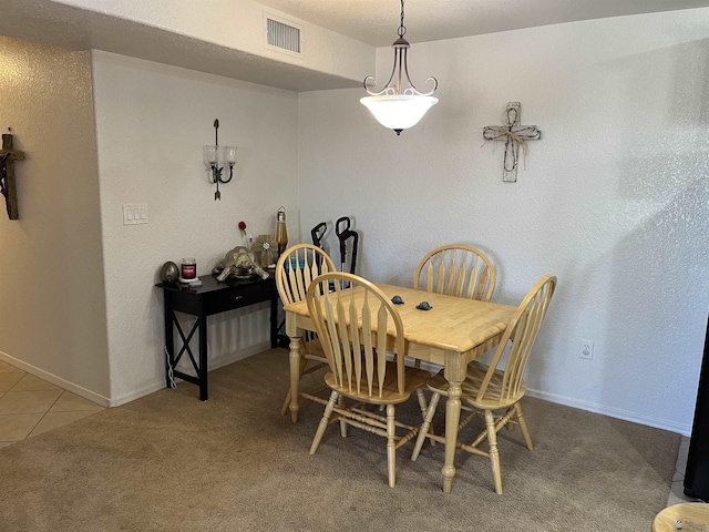 carpeted dining room featuring tile patterned flooring, baseboards, and visible vents