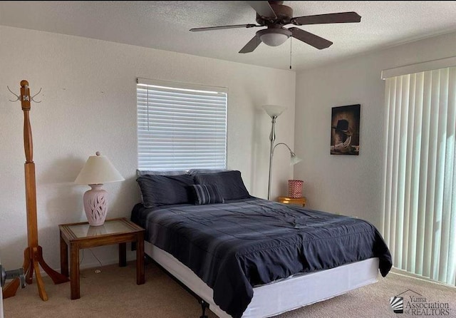 bedroom featuring light carpet, a textured ceiling, and a ceiling fan