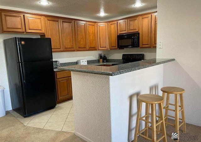 kitchen featuring black appliances, light tile patterned floors, and brown cabinets