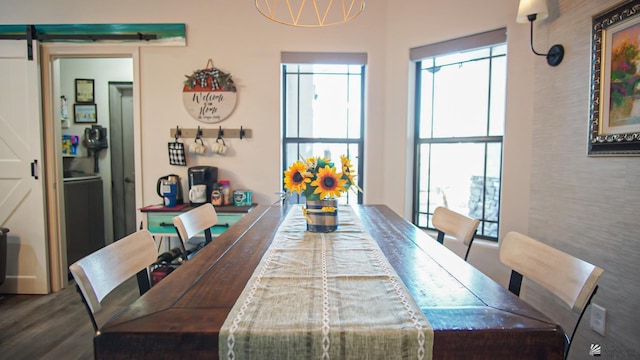 dining room with a barn door and dark wood-type flooring