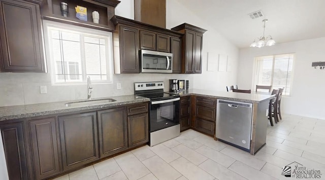 kitchen with visible vents, lofted ceiling, a sink, stainless steel appliances, and a notable chandelier