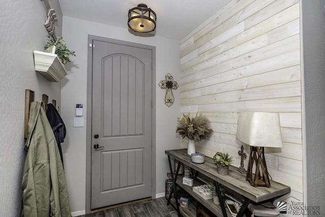 entrance foyer with dark hardwood / wood-style floors and wooden walls