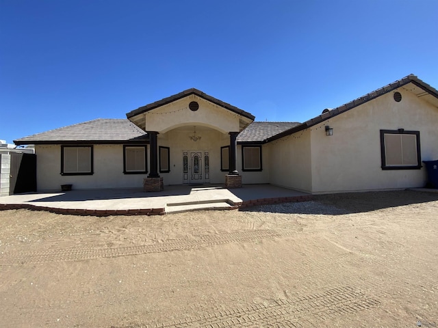 view of front of house with a patio area, a tiled roof, and stucco siding