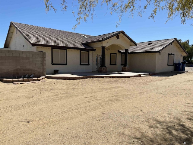 rear view of house with a patio, a tile roof, fence, and stucco siding