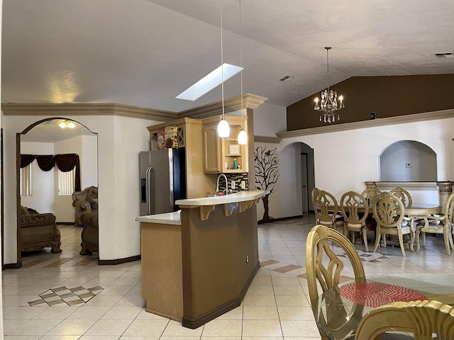 kitchen with arched walkways, decorative light fixtures, stainless steel refrigerator with ice dispenser, light tile patterned floors, and light countertops