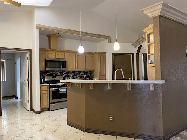 kitchen with appliances with stainless steel finishes, arched walkways, pendant lighting, and a kitchen bar