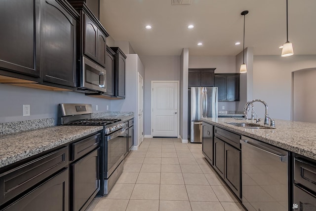 kitchen featuring light stone counters, recessed lighting, a sink, stainless steel appliances, and decorative light fixtures