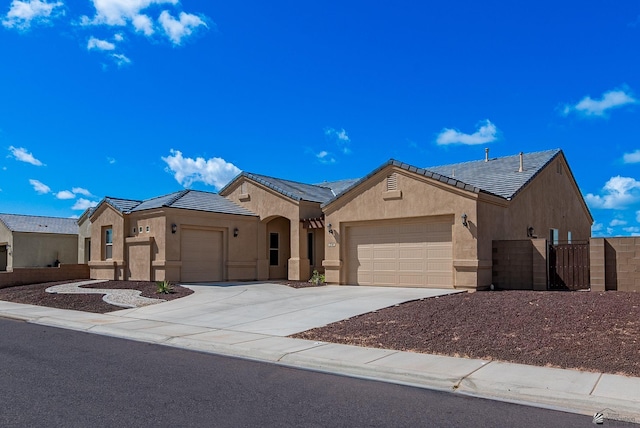 view of front of home with stucco siding, a tile roof, fence, concrete driveway, and a garage