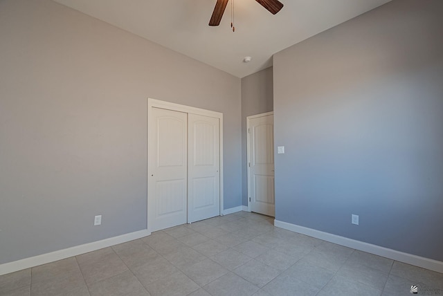 unfurnished bedroom with a closet, light tile patterned floors, a ceiling fan, and baseboards