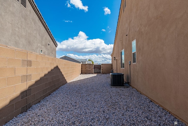 view of yard with central AC, a fenced backyard, and a gate