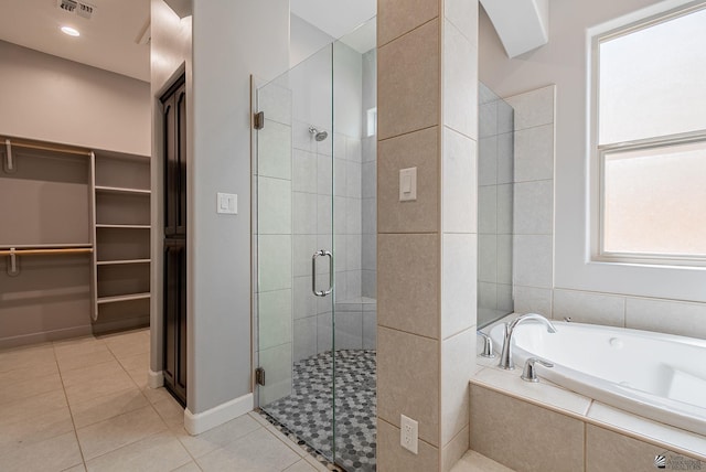 bathroom with a walk in closet, a shower stall, a bath, and tile patterned floors