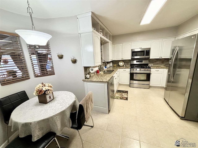 kitchen featuring backsplash, sink, appliances with stainless steel finishes, decorative light fixtures, and white cabinetry